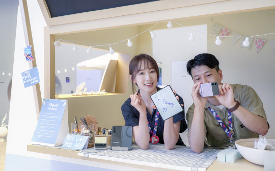 SK텔레콤 직원들이 홍대 ICT멀티플렉스 T팩토리에 설치된 폴더블 체험존을 소개하고 있다. SK텔레콤 제공